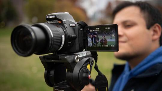 student filming with a camera